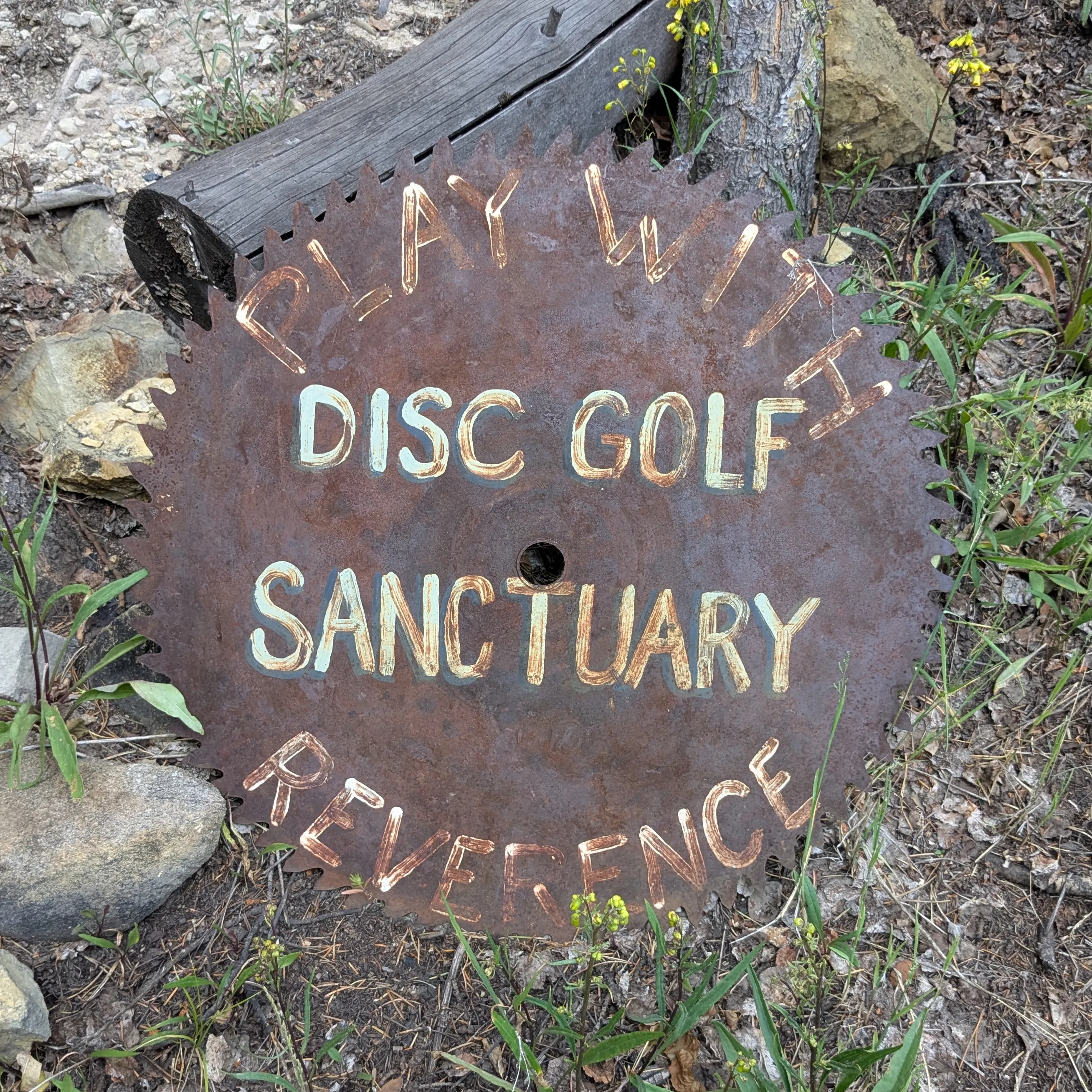 A rusty saw blade reading "Disc Golf Sanctuary"